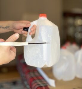Cutting around an empty milk jug with scissors