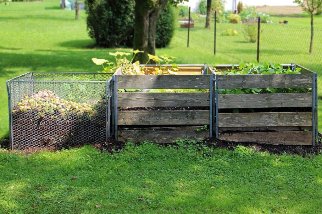 Three compost bins made out of steel fencing and wood sit along side each other in a yard.