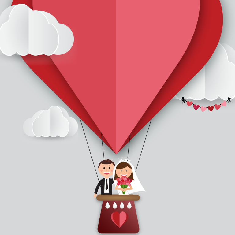 A married couple ride in the basket of a red heart-shaped balloon.